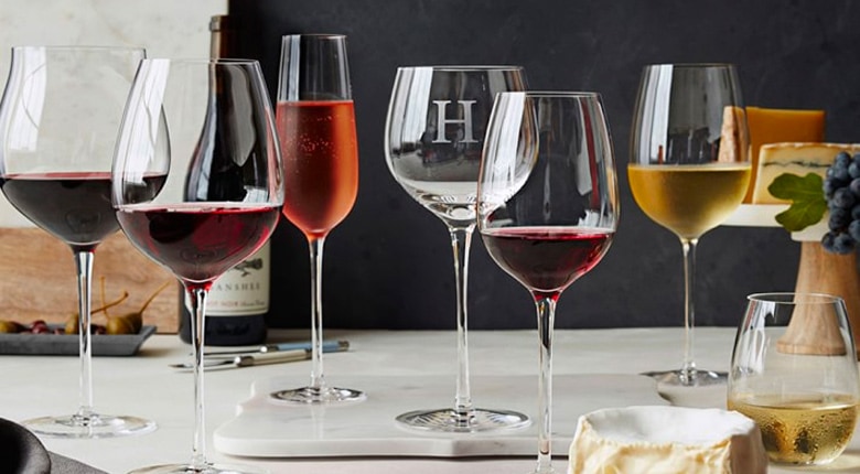 Different types of wine glasses containing red, white and rose wine surrounded by food options for wine pairing.
