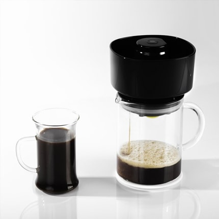Vacuum coffee brewer brewing coffee into a glass carafe next to a glass mug of coffee.