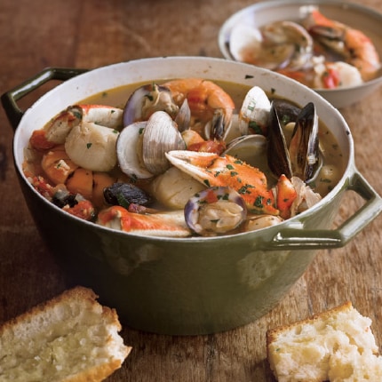 Cioppino with clams, scallops and shrimp in a large pot served with toasted baguettes.