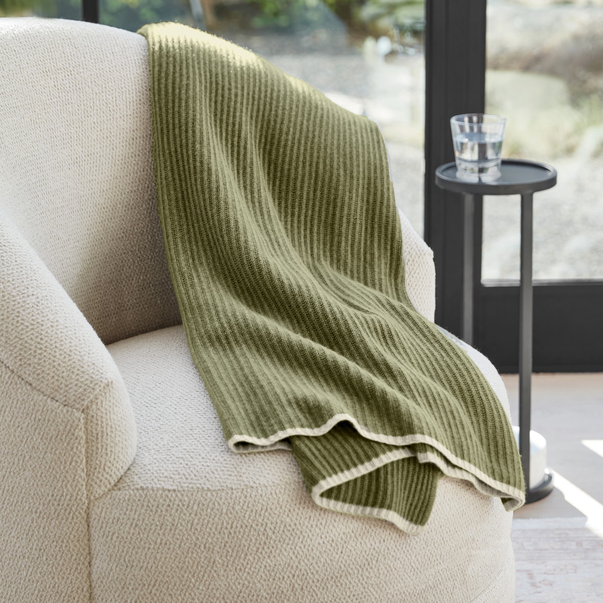 green cashmere throw over a white chair. 