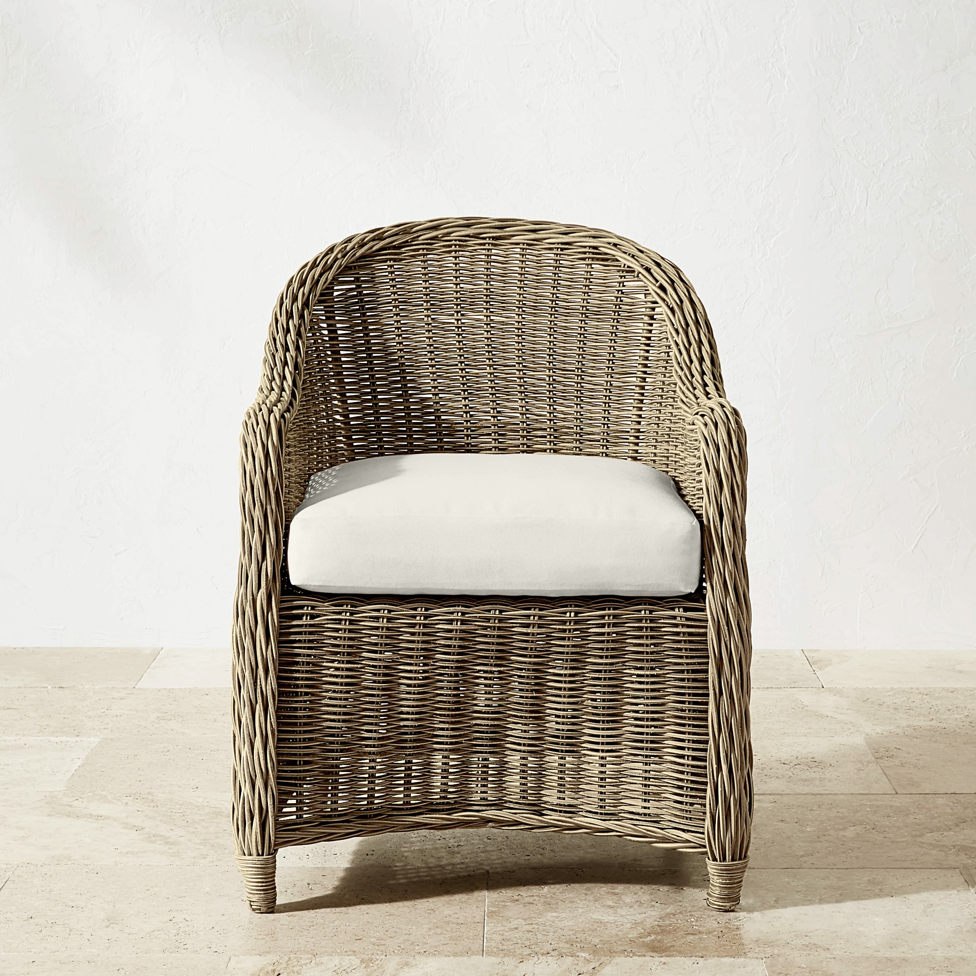 Single wicker armchair with light cushion on a light floor