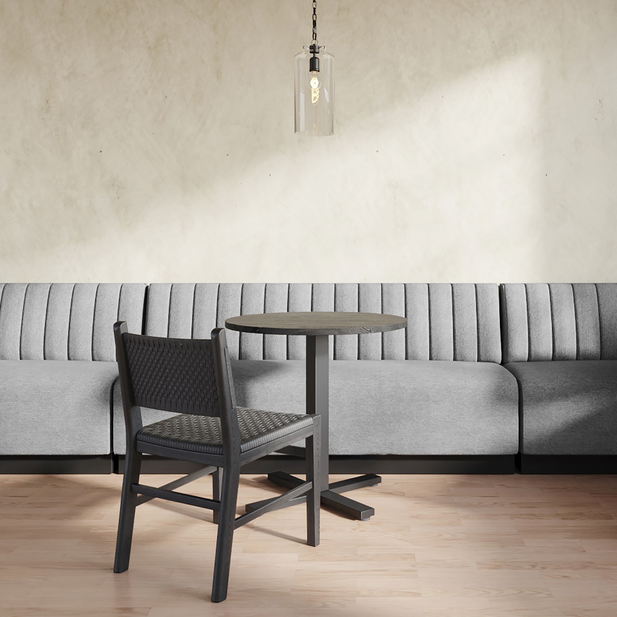 Round table with single chair and long gray sofa in a contemporary dining area.
