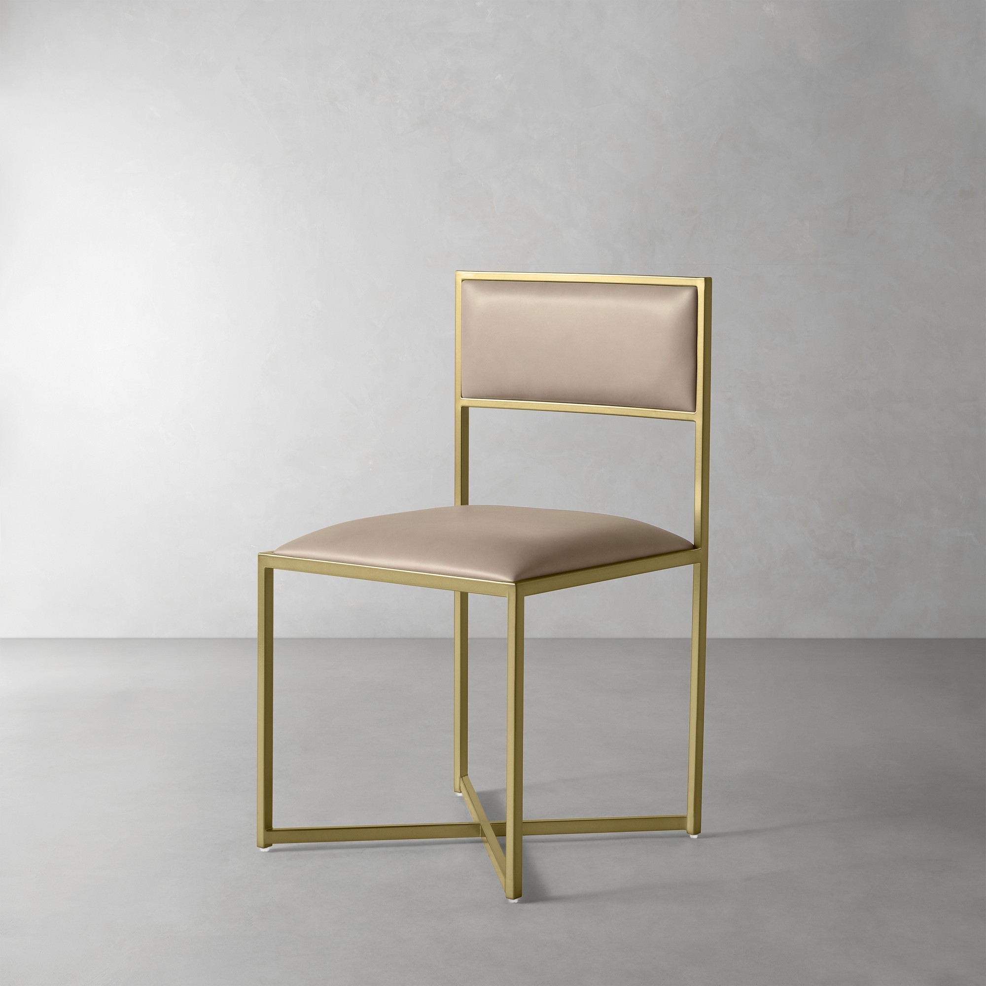 Rear three-quarter view of a gold framed tan upholstered chair in a studio.