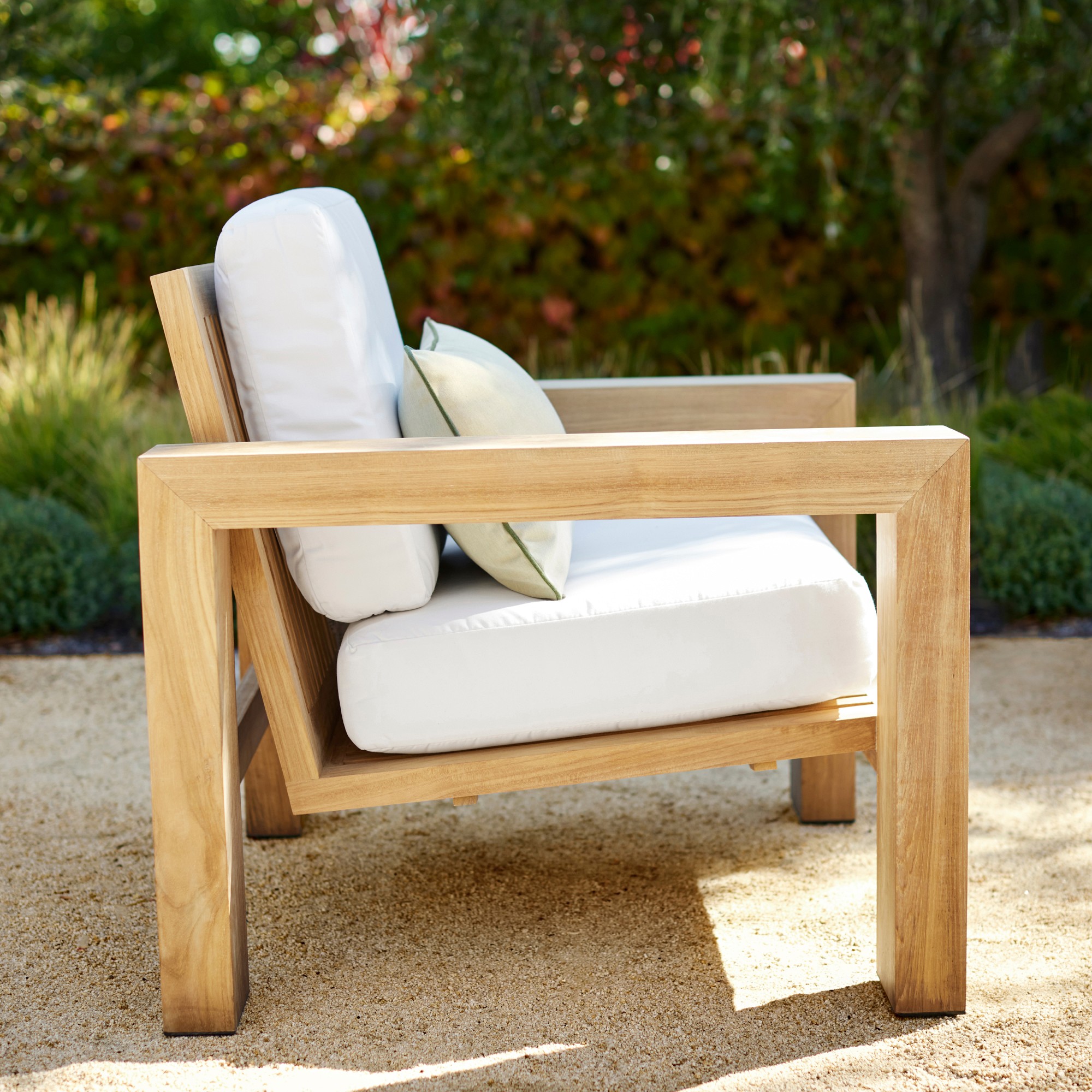 Single white cushioned outdoor lounge chair showing side wood frame