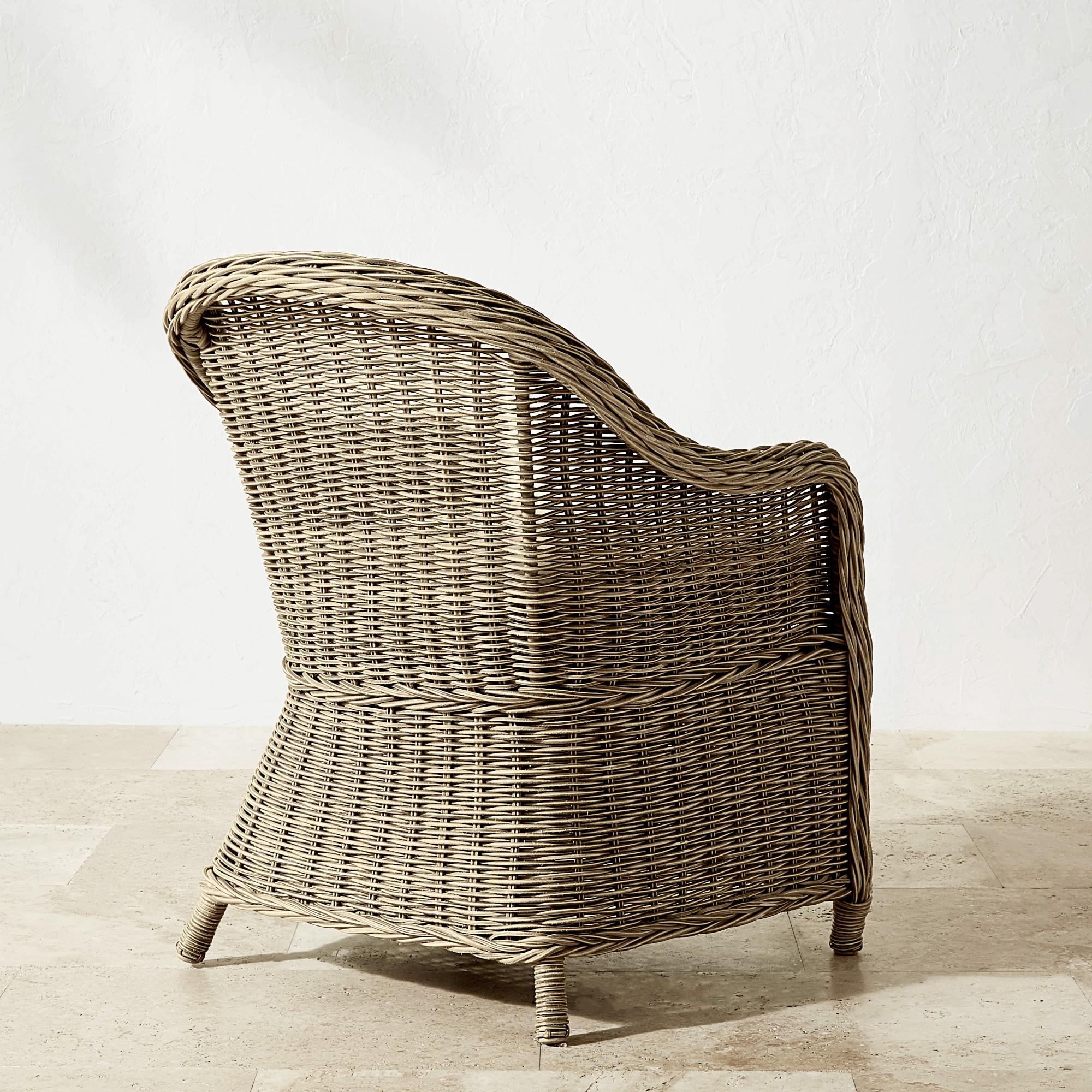 Side view of a brown wicker chair with curved back and woven texture