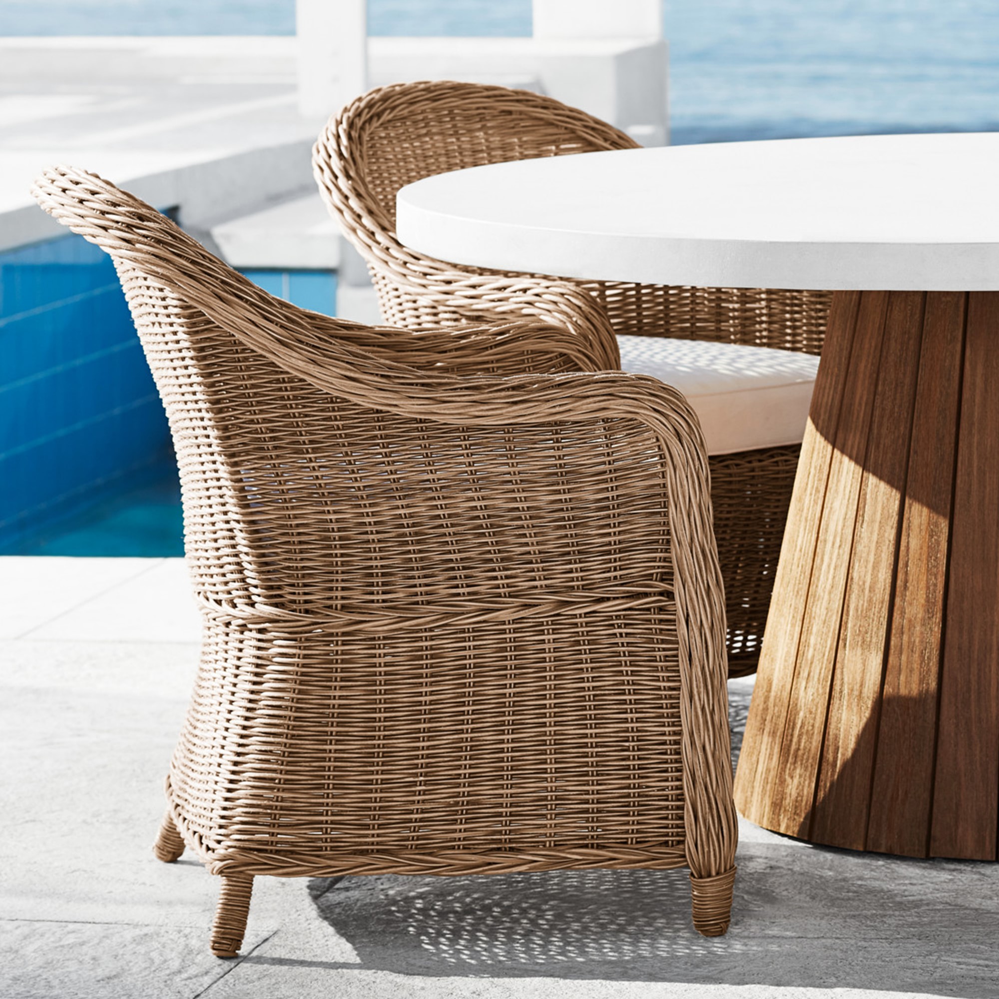 Wicker chair with round white table near pool