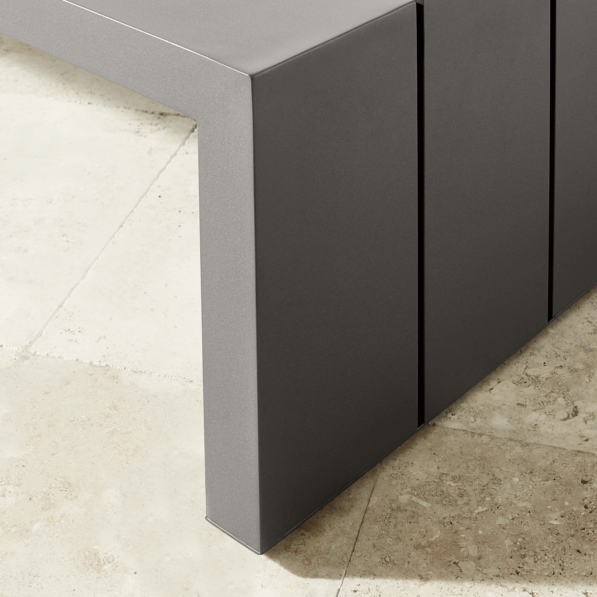 Corner detail of the gray bench showing leg and panel joints
