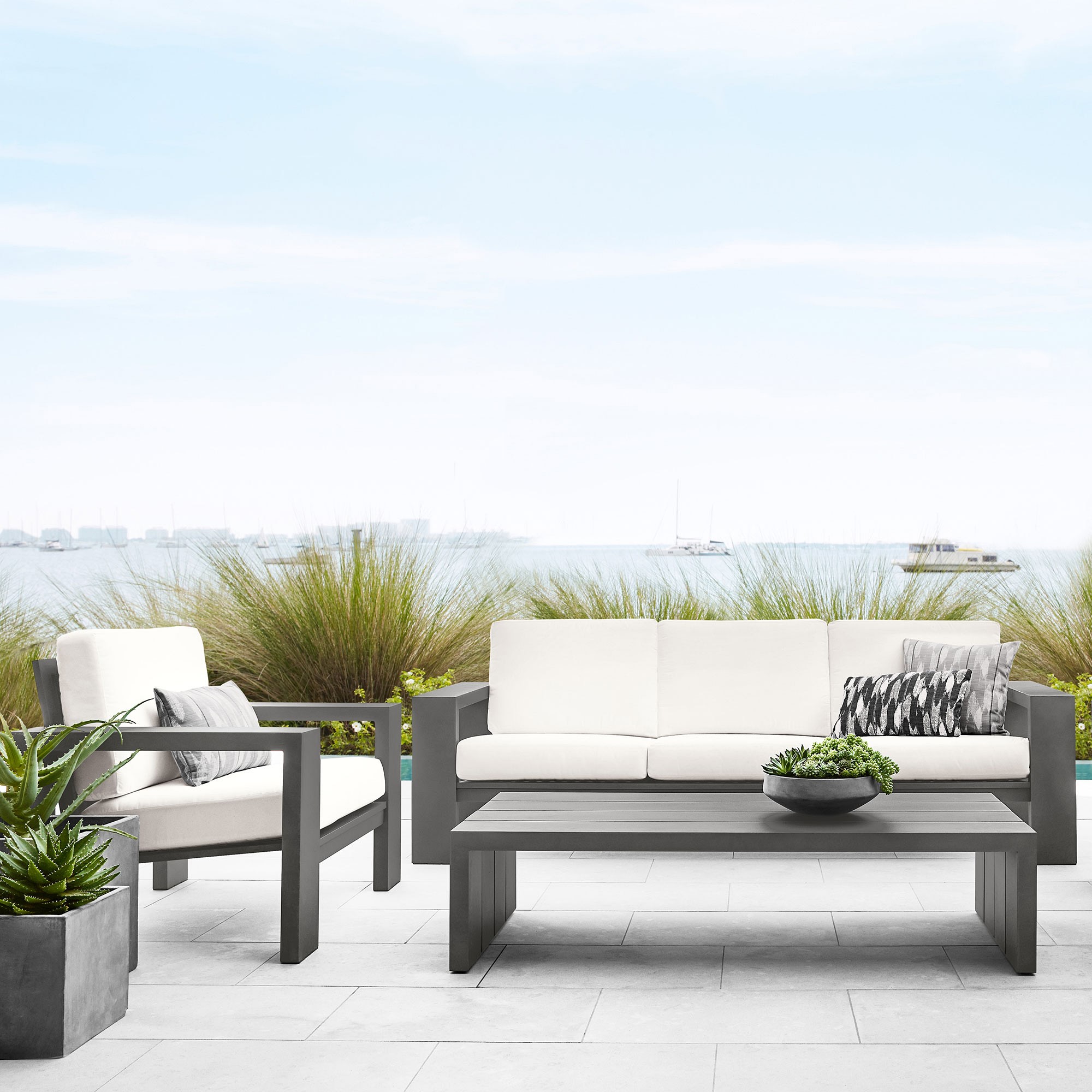 Outdoor seating area with white cushions and a gray low coffee table on a patio