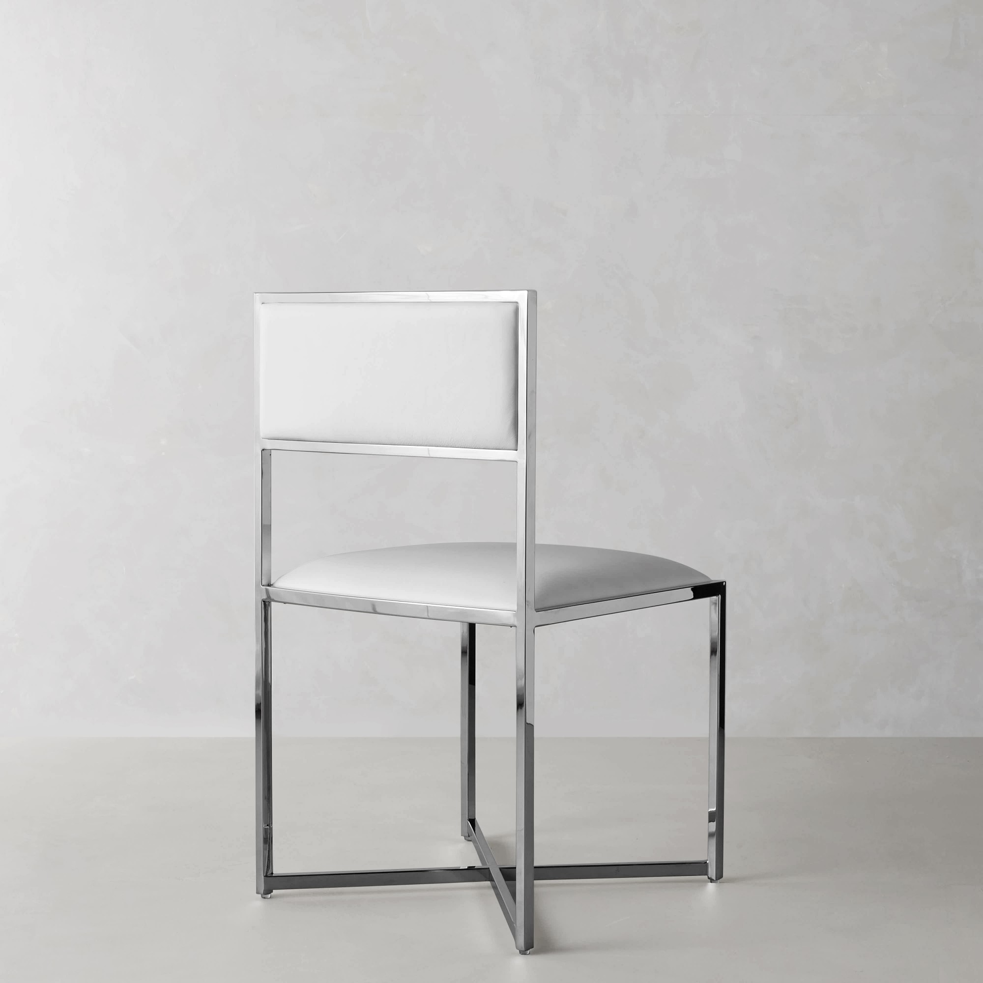 Profile view of a white upholstered dining chair with chrome frame showing its geometric rectangular legs.