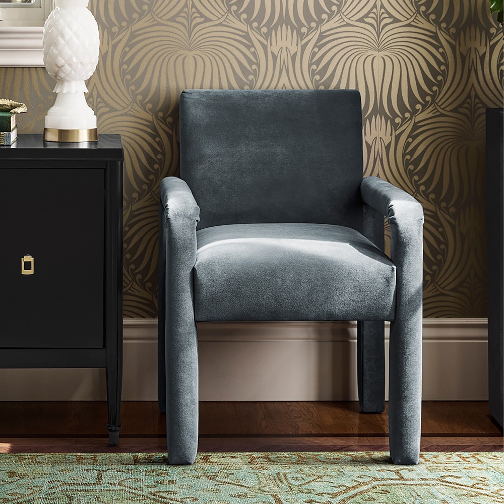 Blue upholstered dining chair against patterned wallpaper