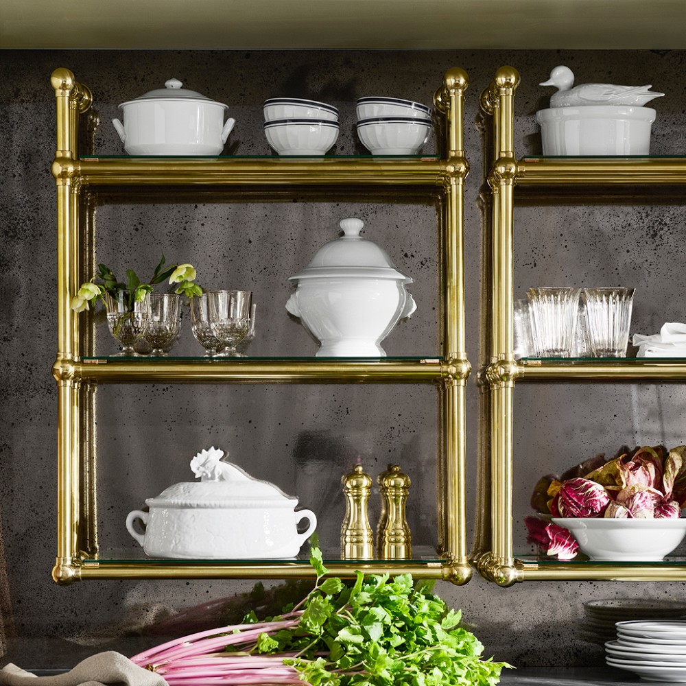 Close-up of brass frame and glass shelf with white dishware