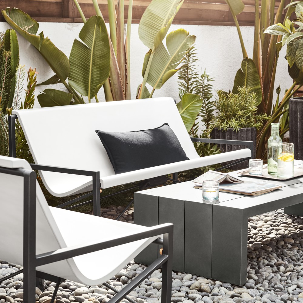 White outdoor sofa with black frame against a tropical backdrop