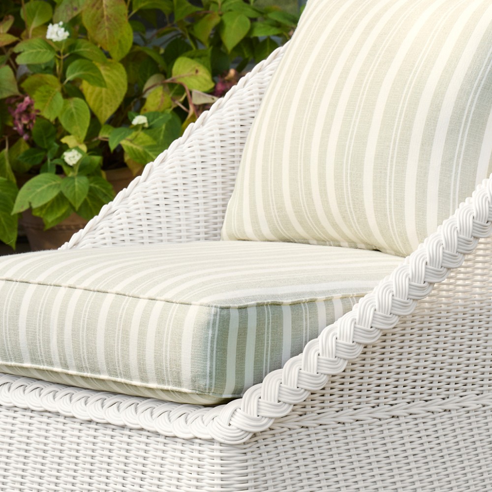 Close-up of striped cushion and arm of white wicker chair