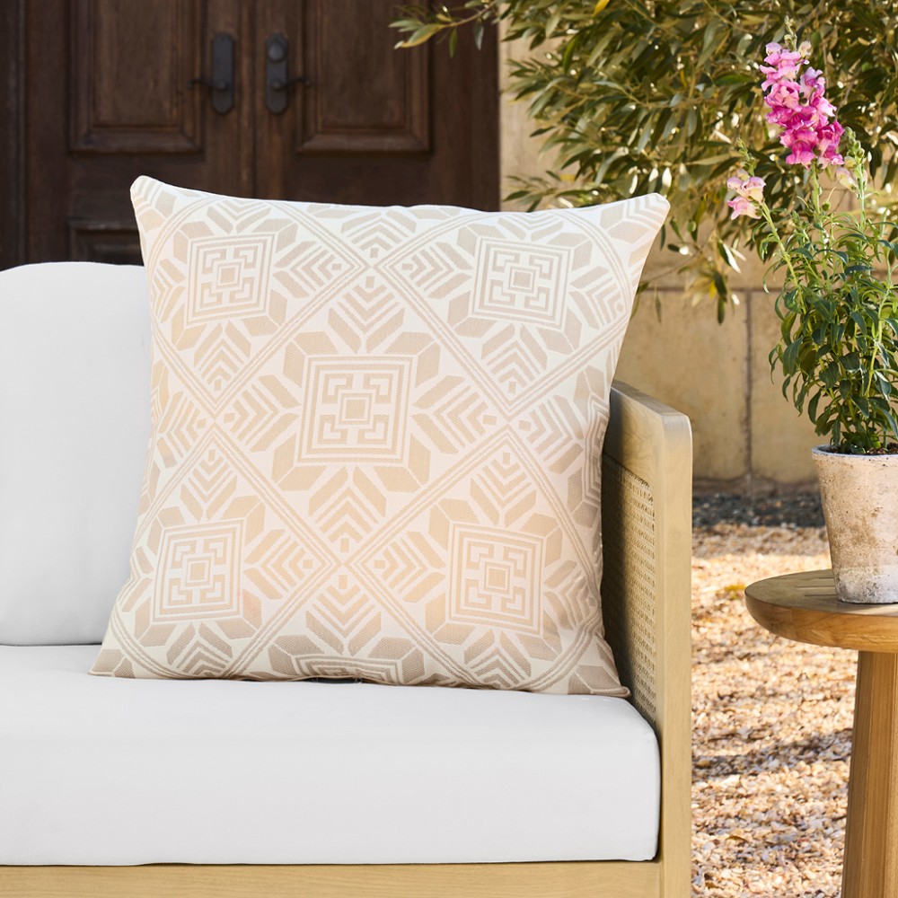 Beige/cream geometric patterned outdoor pillow on white outdoor chair
