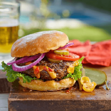 Burger stuffed with pimento cheese on a chopping board.