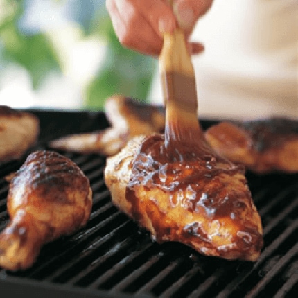 Bourbon molasses chicken being glazed whilst cooking on a grill.