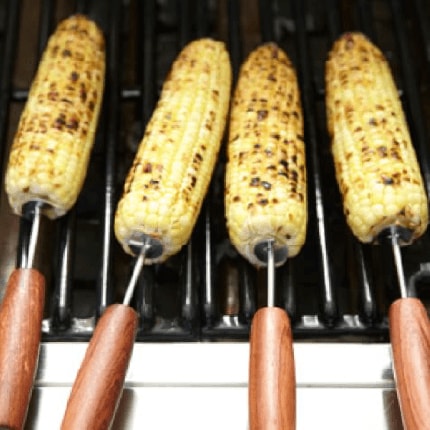 Mexican street corn cooking on a grill.