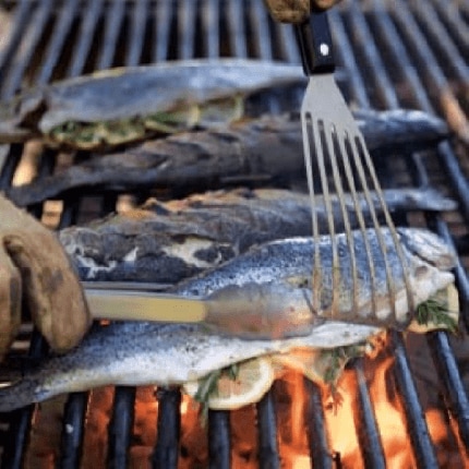 Grilled whole fish stuffed with lemon and herbs cooking on a grill.