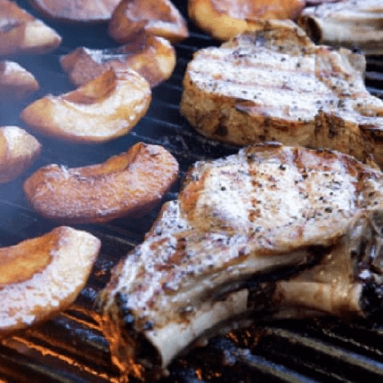 Pork chops with grilled apple puree cooking on a grill.