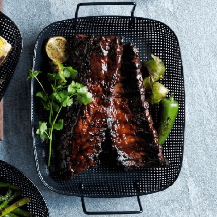 Baby back ribs with bourbon black pepper sauce in a serving dish.