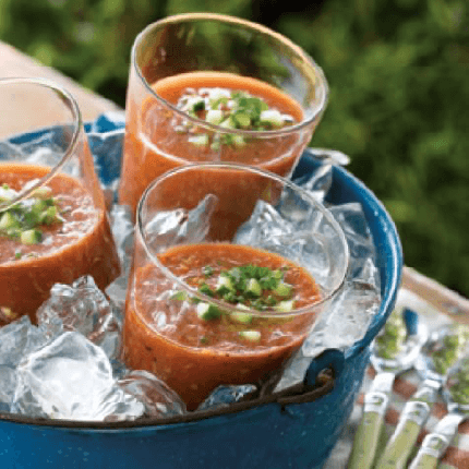 Three glasses of grilled gazpacho in a bucket full of ice.