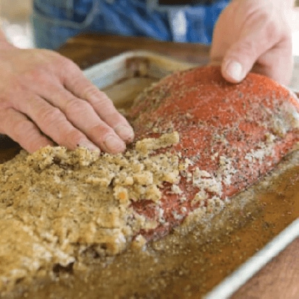 Salmon filet being massaged with horseradish rub.