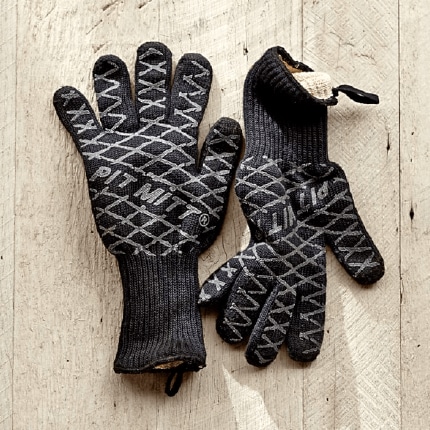 Pair of grilling mitts on wooden boards.