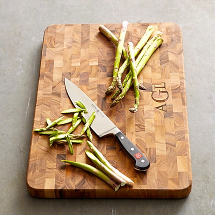Wusthof classic chef’s knife with asparagus on a wooden cutting board.