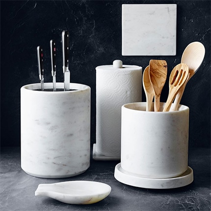 Williams Sonoma white marble kitchen utensil holder on dark marble countertop.