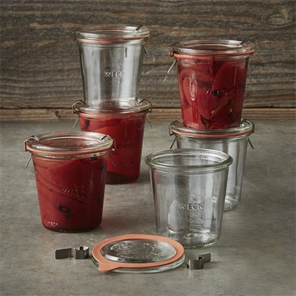 Set of glass Weck jars with sealing lids containing pickled vegetables.