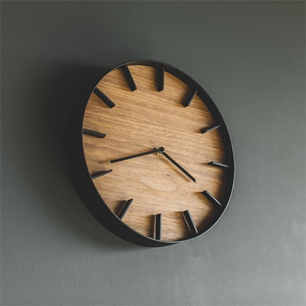 A wooden Yamazaki Home Rin kitchen wall clock hanging on a kitchen wall.