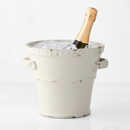 A bottle of champagne inside a rustic champagne bucket filled with ice.