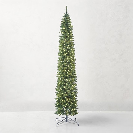 A faux empire pencil Christmas tree with lights in front of a white wall.