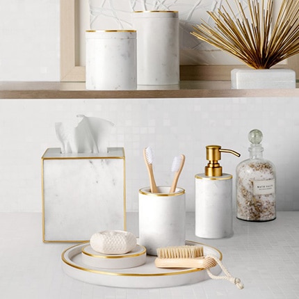 Several matching white bathroom vanity accessories including tray, tissue dispenser, toothbrush holder and soap dispenser.