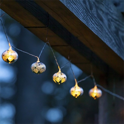 A string of solar string lights hanging from a wooden beam.