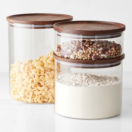 A set of three Hold Everything stacking glass canisters with macaroni noodles, flour and dried beans.