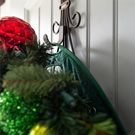 A holiday wreath hanging from a Williams Sonoma wreath door protector. 