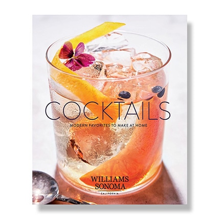The cover of the Williams Sonoma Test Kitchen cocktails cookbook featuring a cocktail with a flower, berries and orange peel.