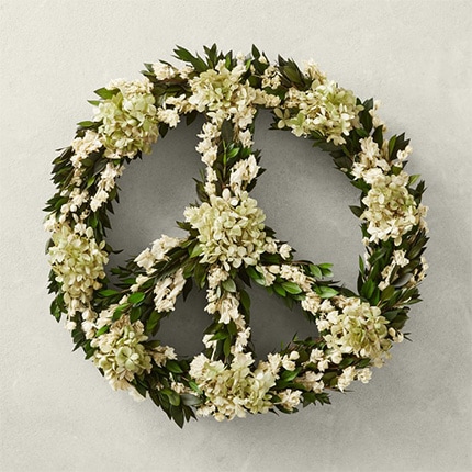 A peace sign wreath hanging on a white wall.