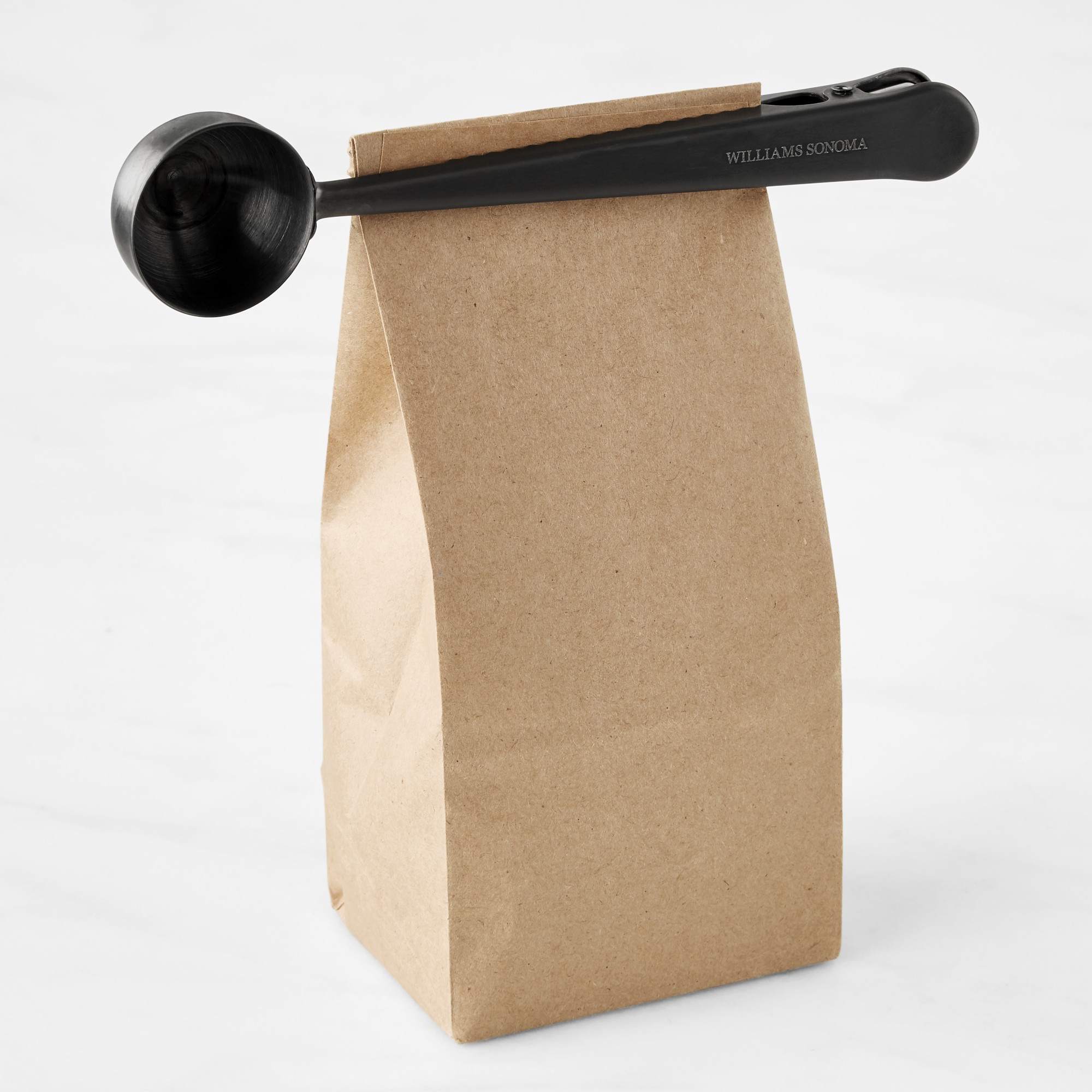 A black coffee scoop clip on a brown paper bag