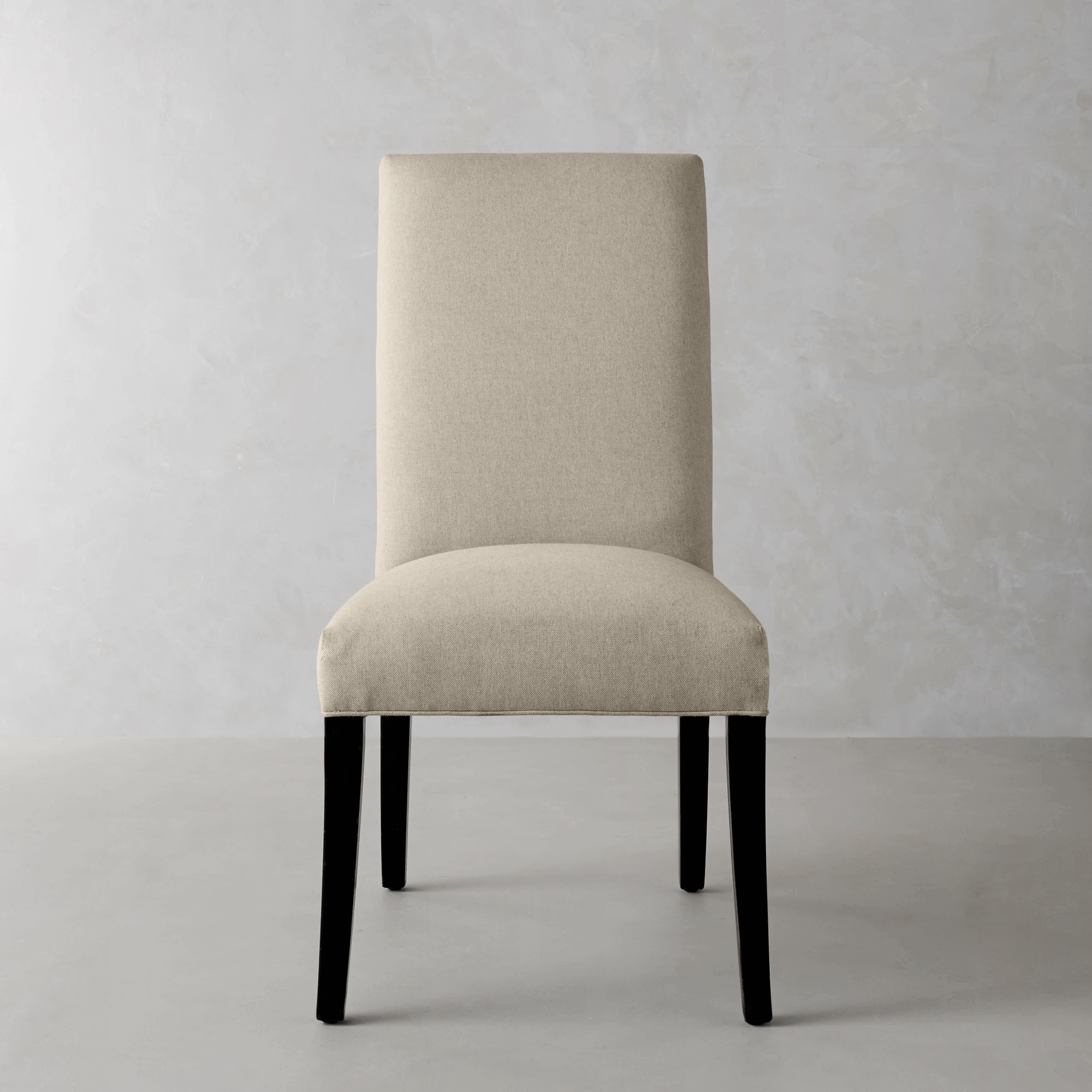 Beige upholstered dining chair front view showing backrest and seat.
