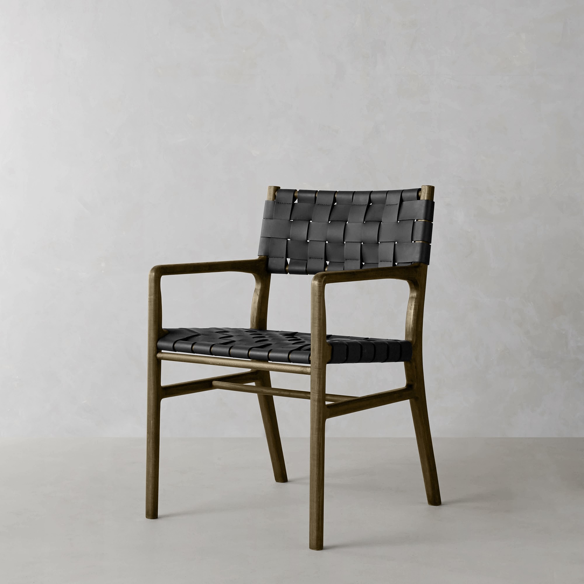 Light wood chair with woven tan leather seat and backrest in a neutral setting.