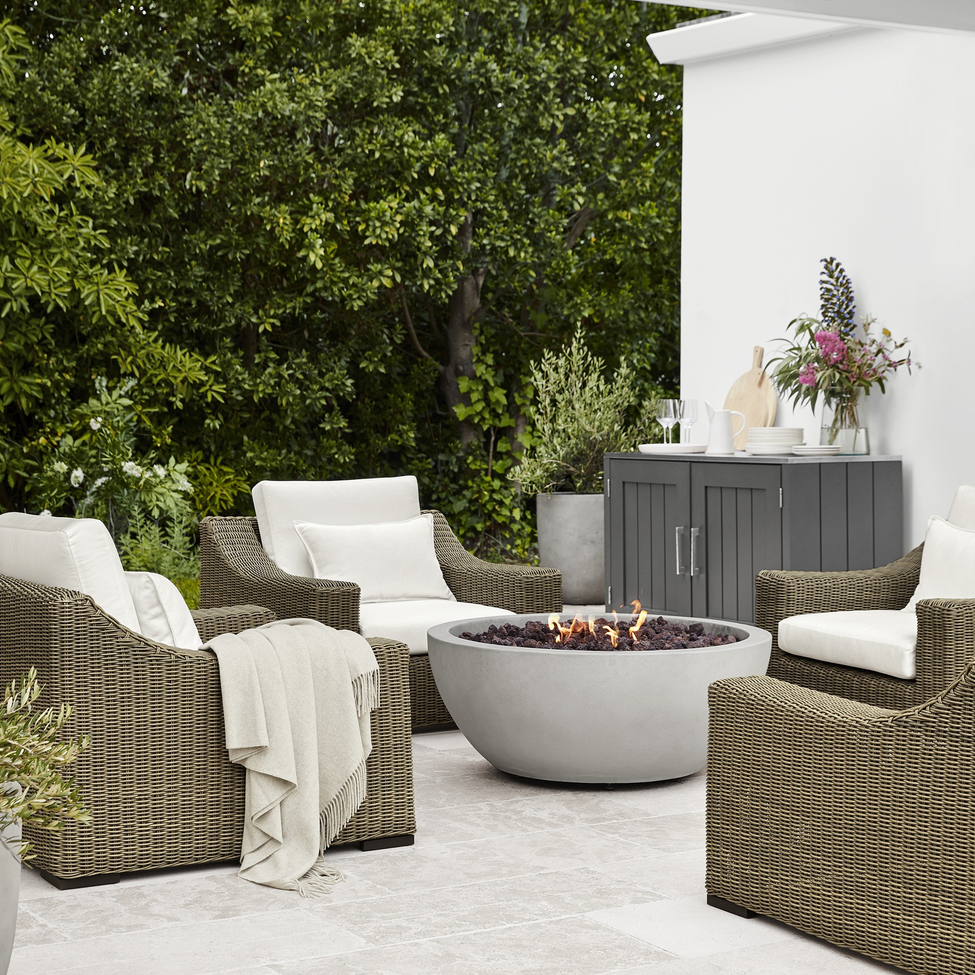Concrete gray fire pit bowl with lava rocks and built-in gas burner visible, LED flame jets around top edge