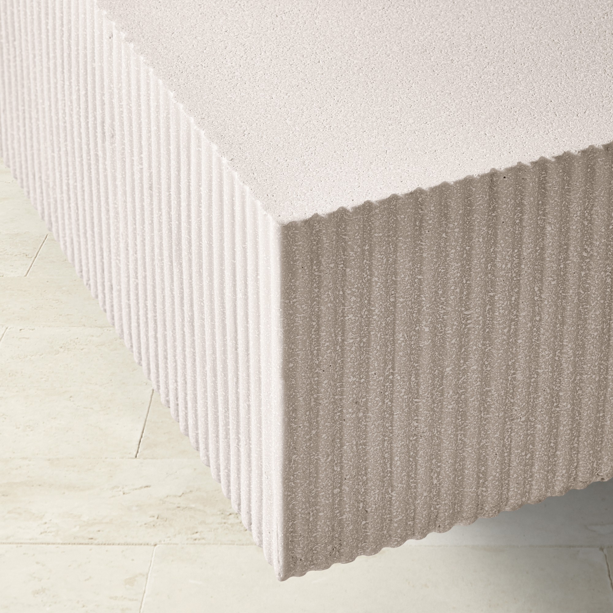 Close-up of the corner of a beige, rectangular coffee table with a ribbed texture.