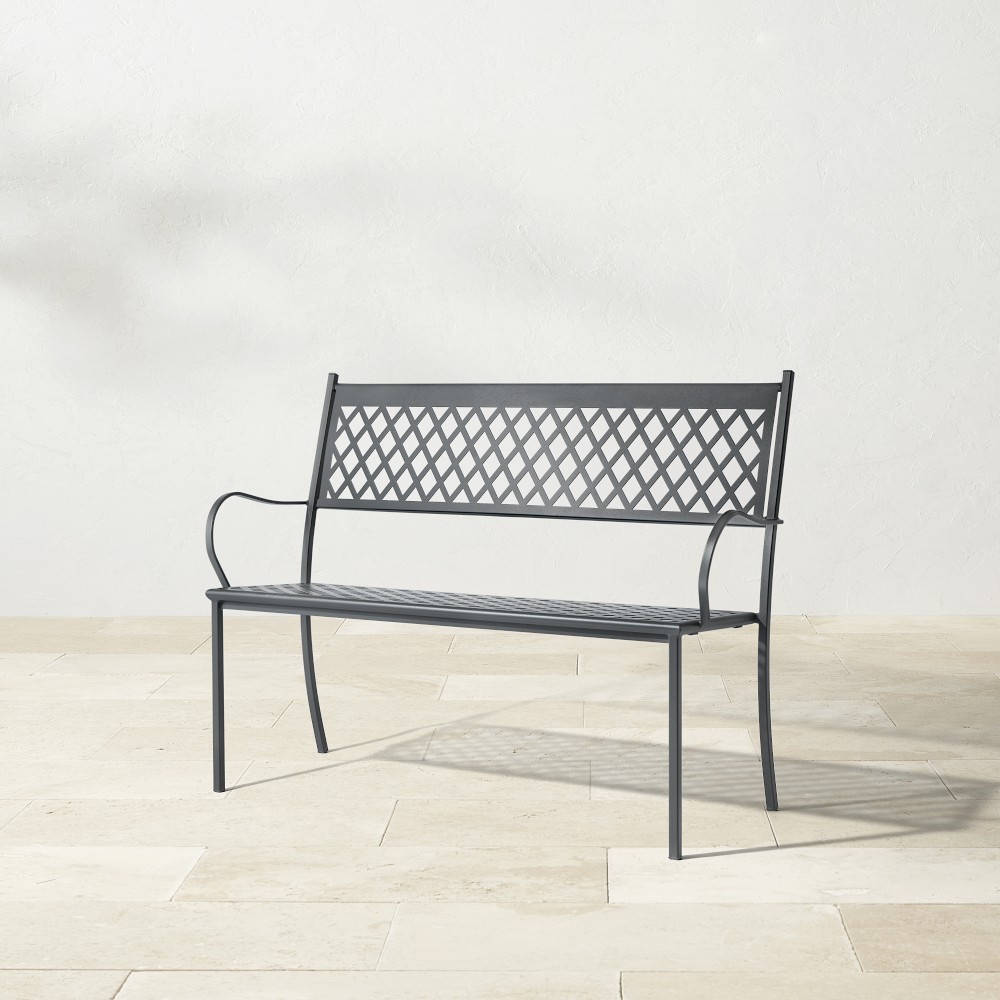 Close-up of metal bench with lattice back and curved arm on white background
