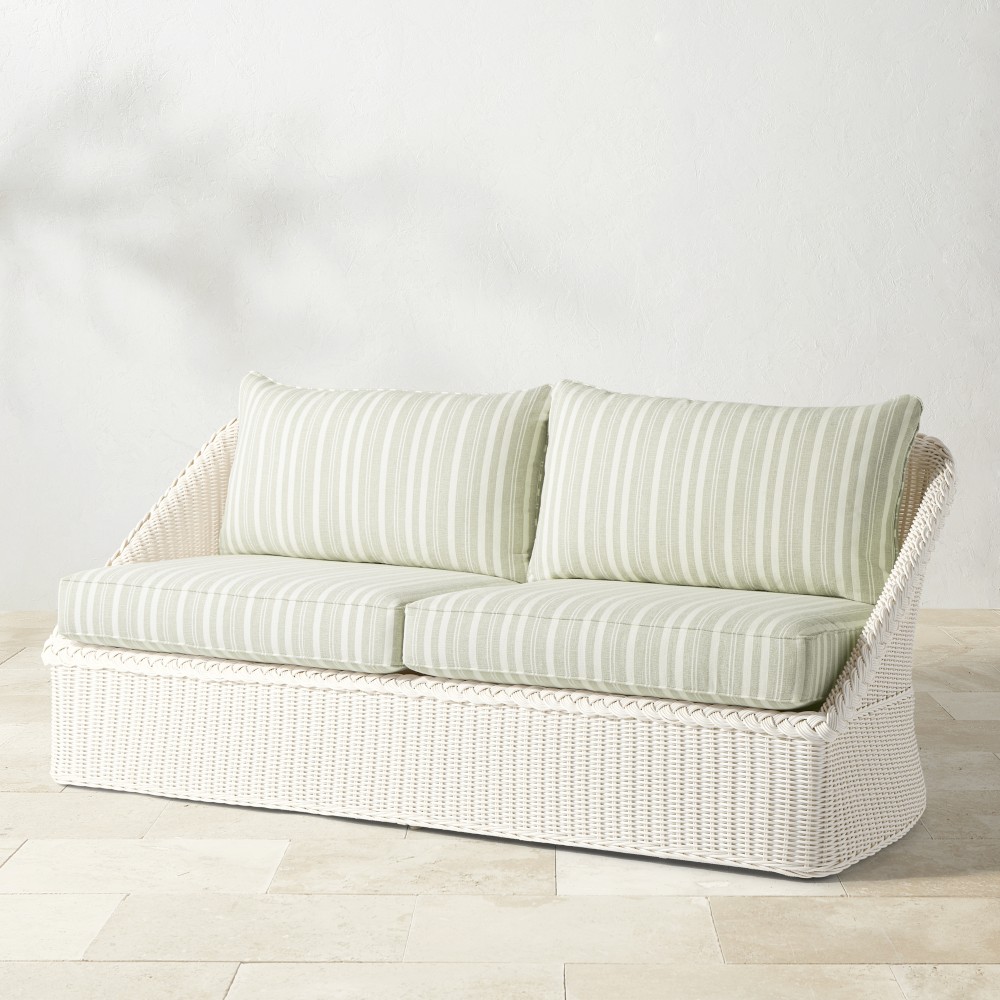 Three-quarter view of white wicker outdoor sofa with striped cushions