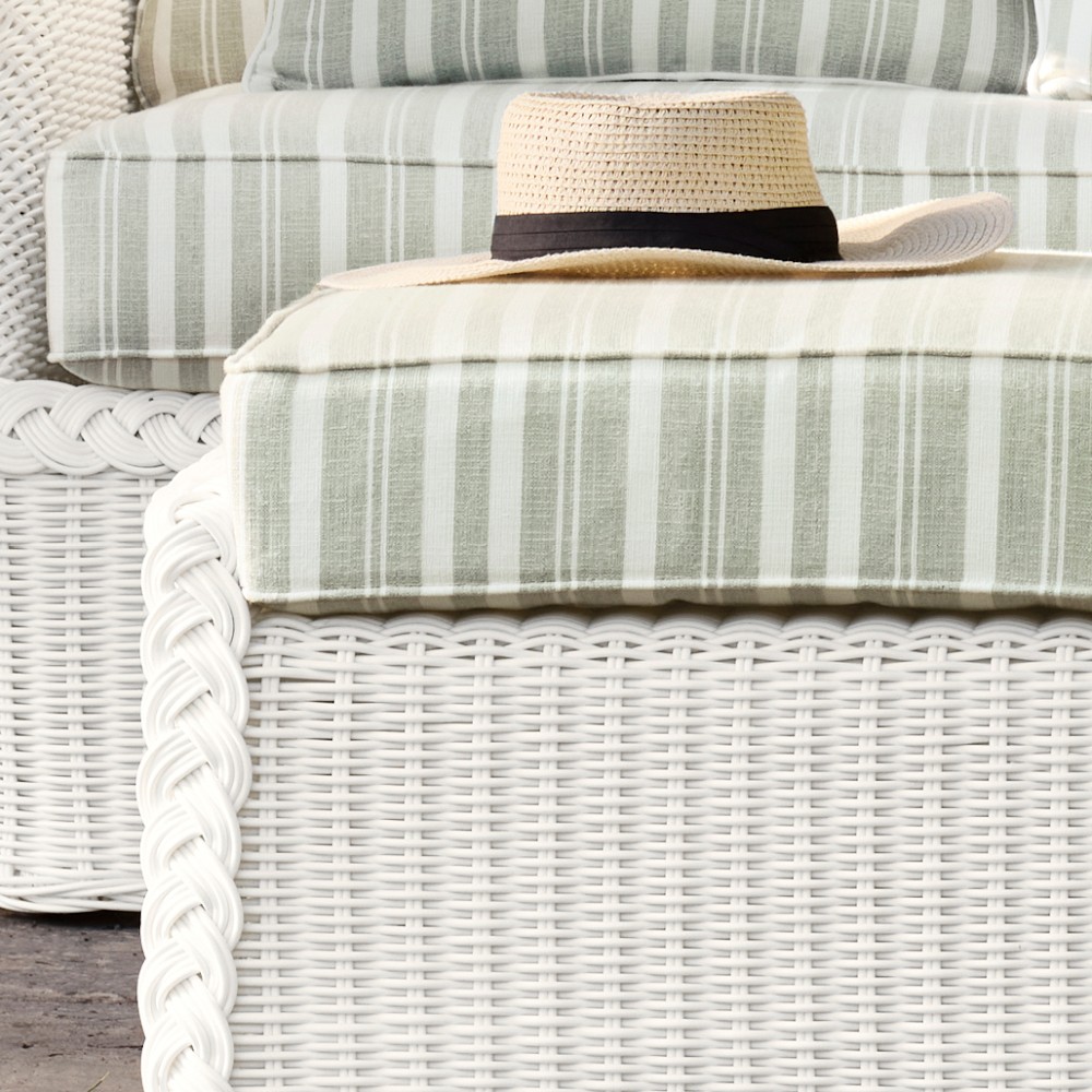 Close-up of wicker base with striped cushion and straw hat