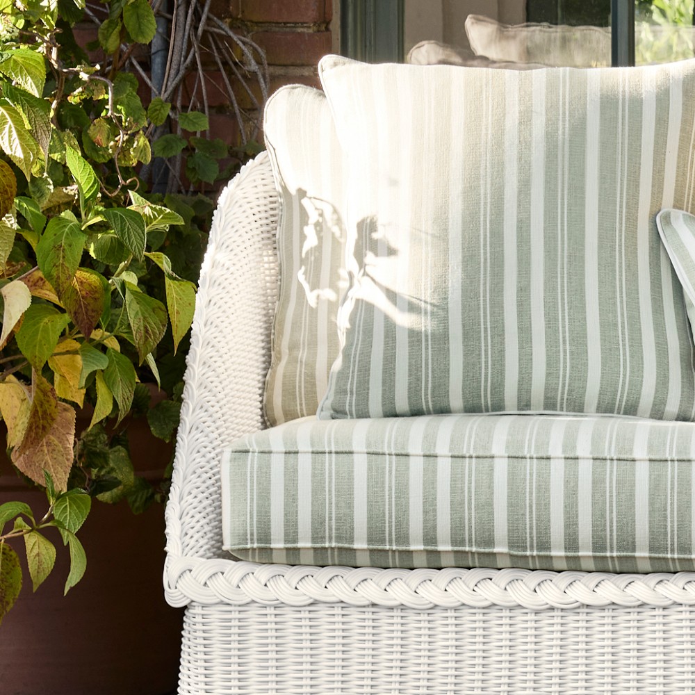 Close-up of left armrest and cushion of white wicker outdoor sofa